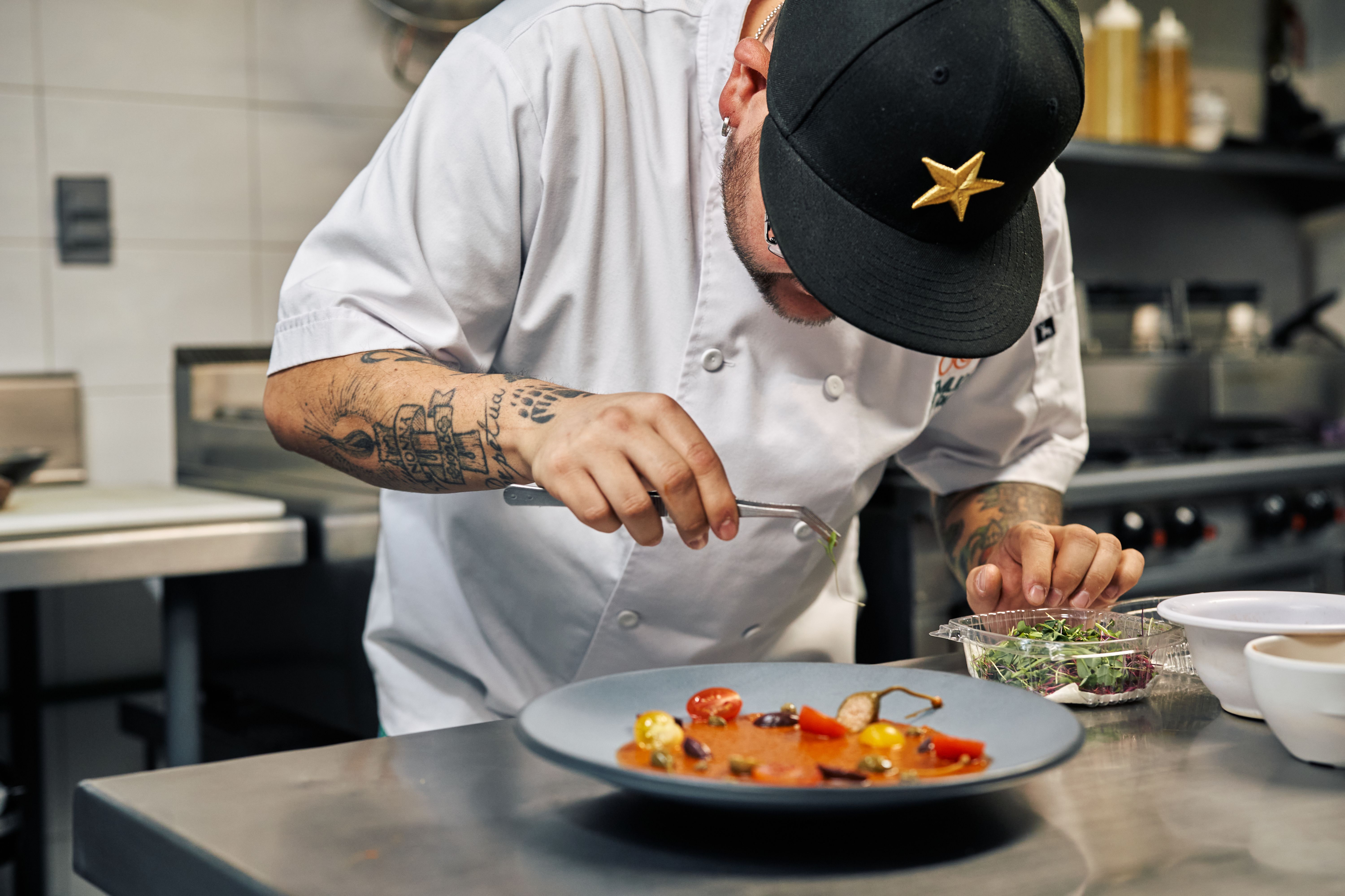 Chef carefully garnishing a gourmet dish with precision in a professional kitchen