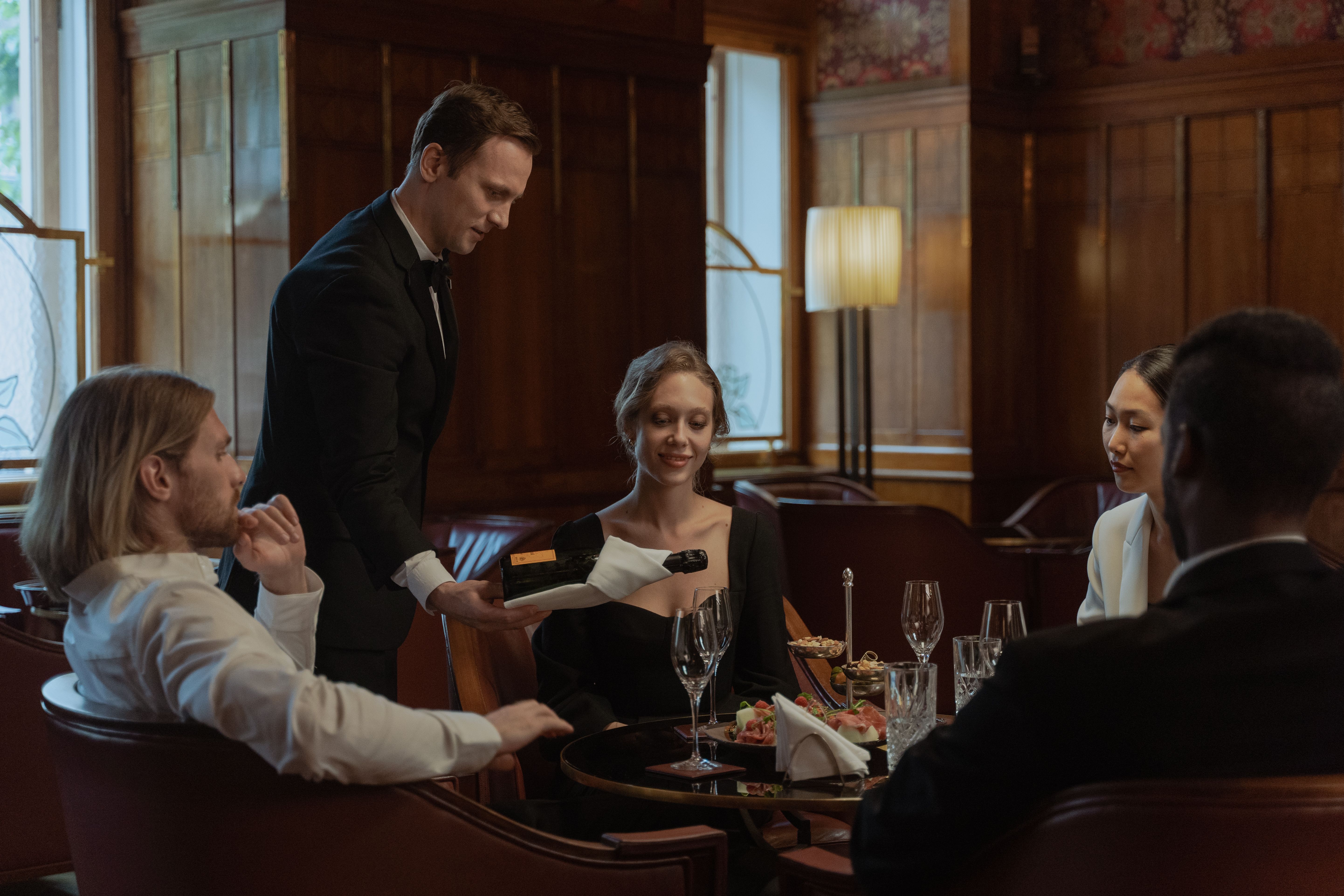 Waiter serving wine to guests enjoying an elegant fine dining meal