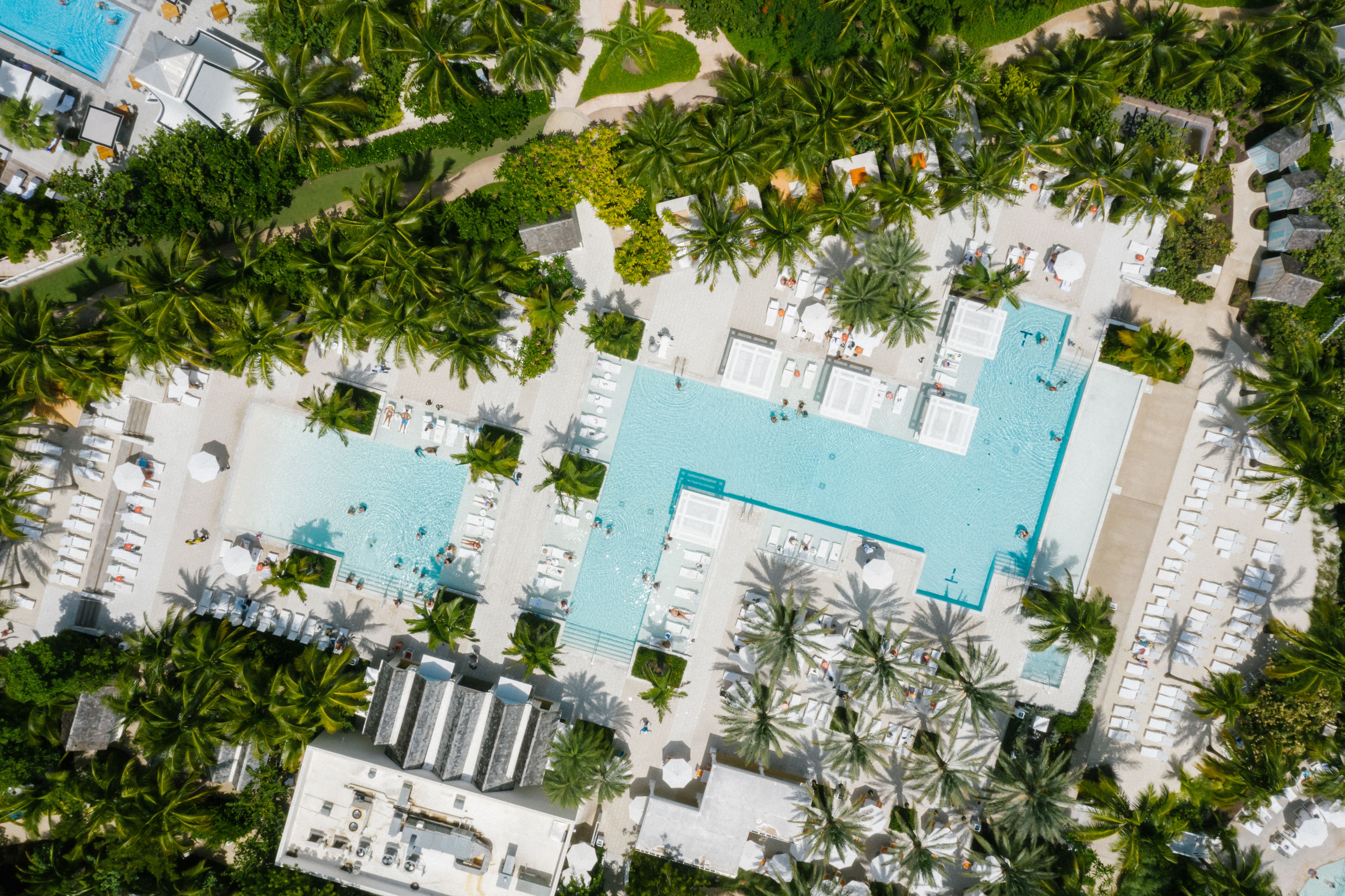 Aerial view of a luxurious resort with swimming pools and lush tropical greenery