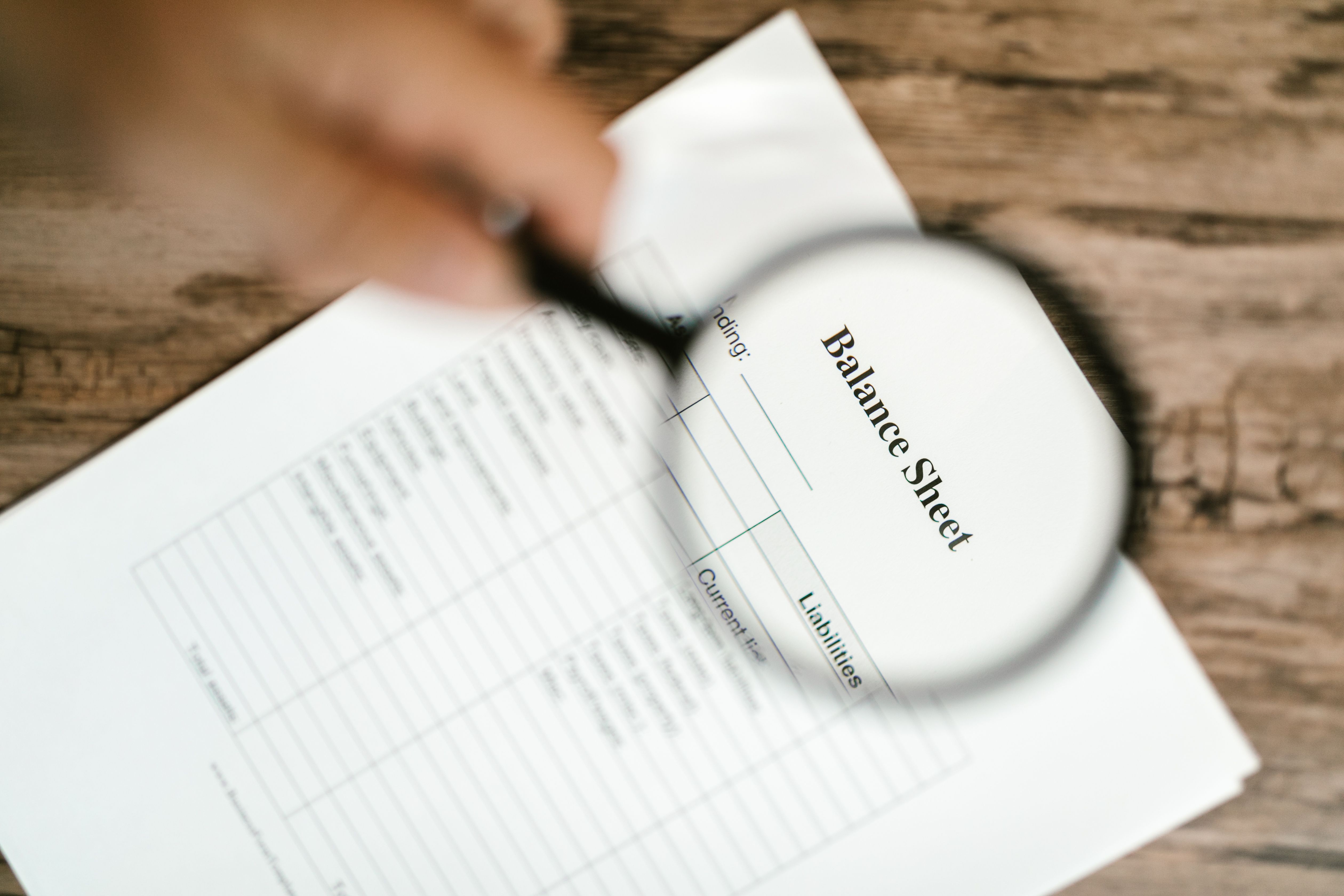 Close-up of a balance sheet under a magnifying glass on a wooden table