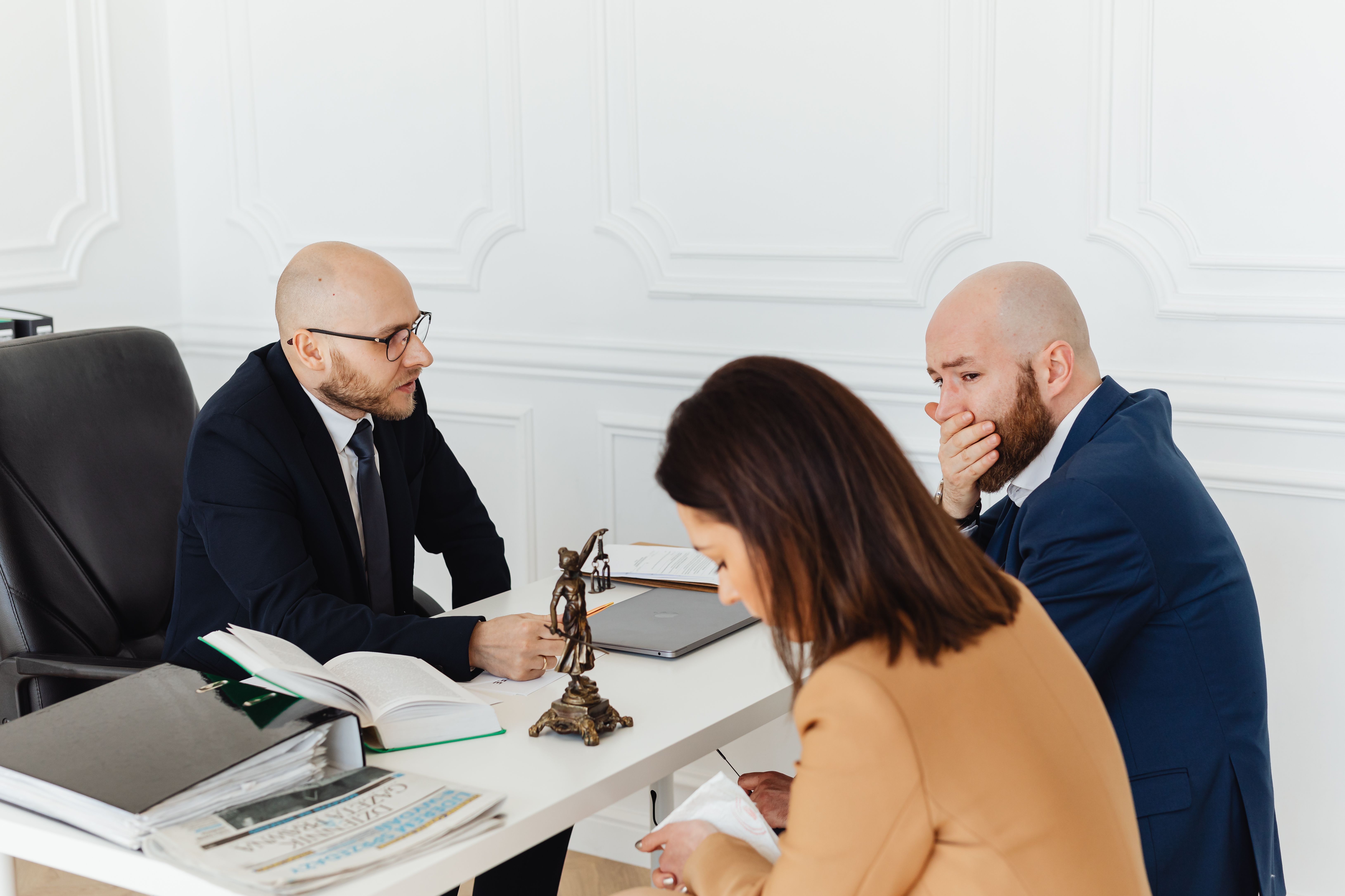 Serious legal consultation in a professional office between a lawyer and clients discussing a large-scale claim
