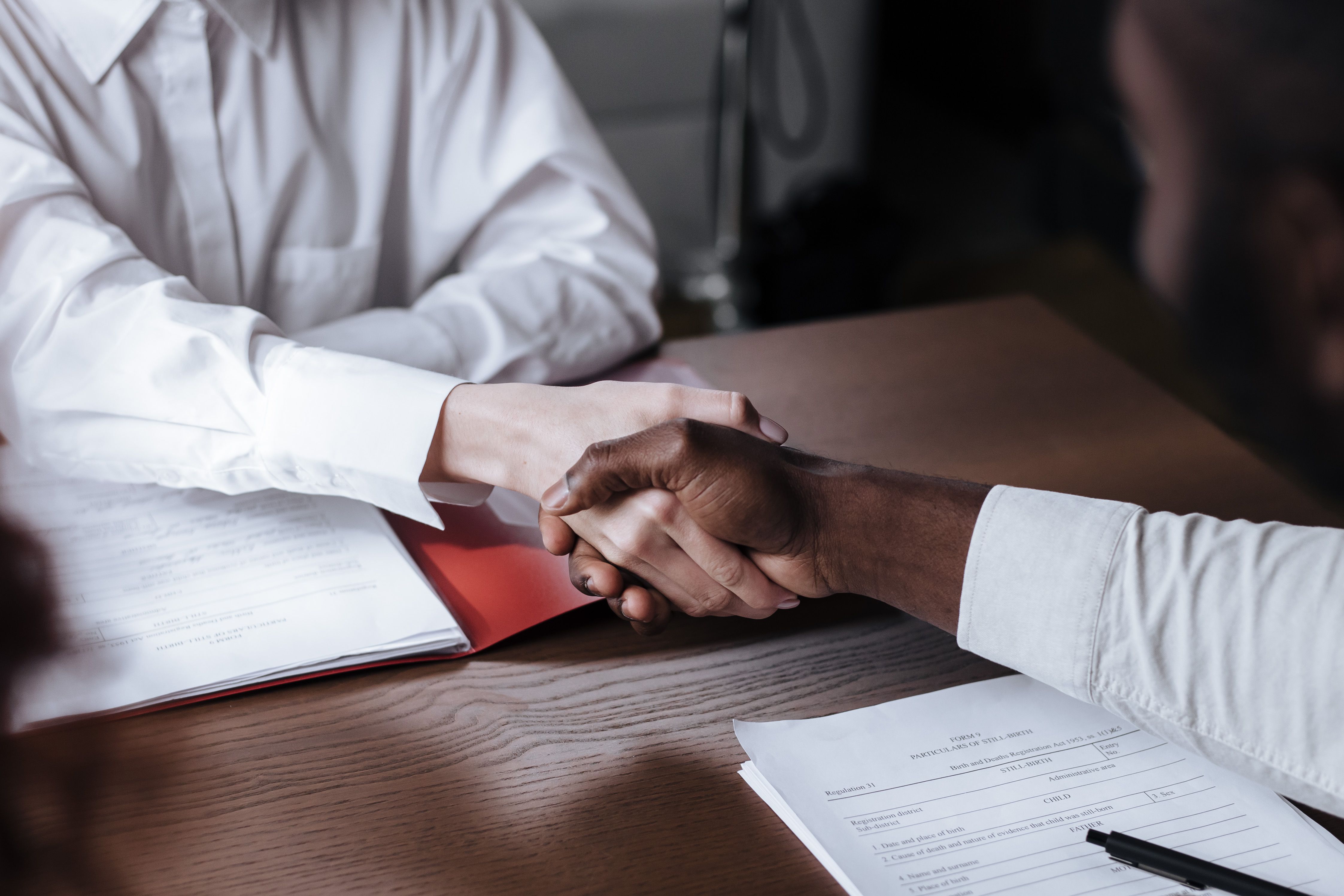 Close-up of a business handshake over legal documents, representing a litigation funding agreement