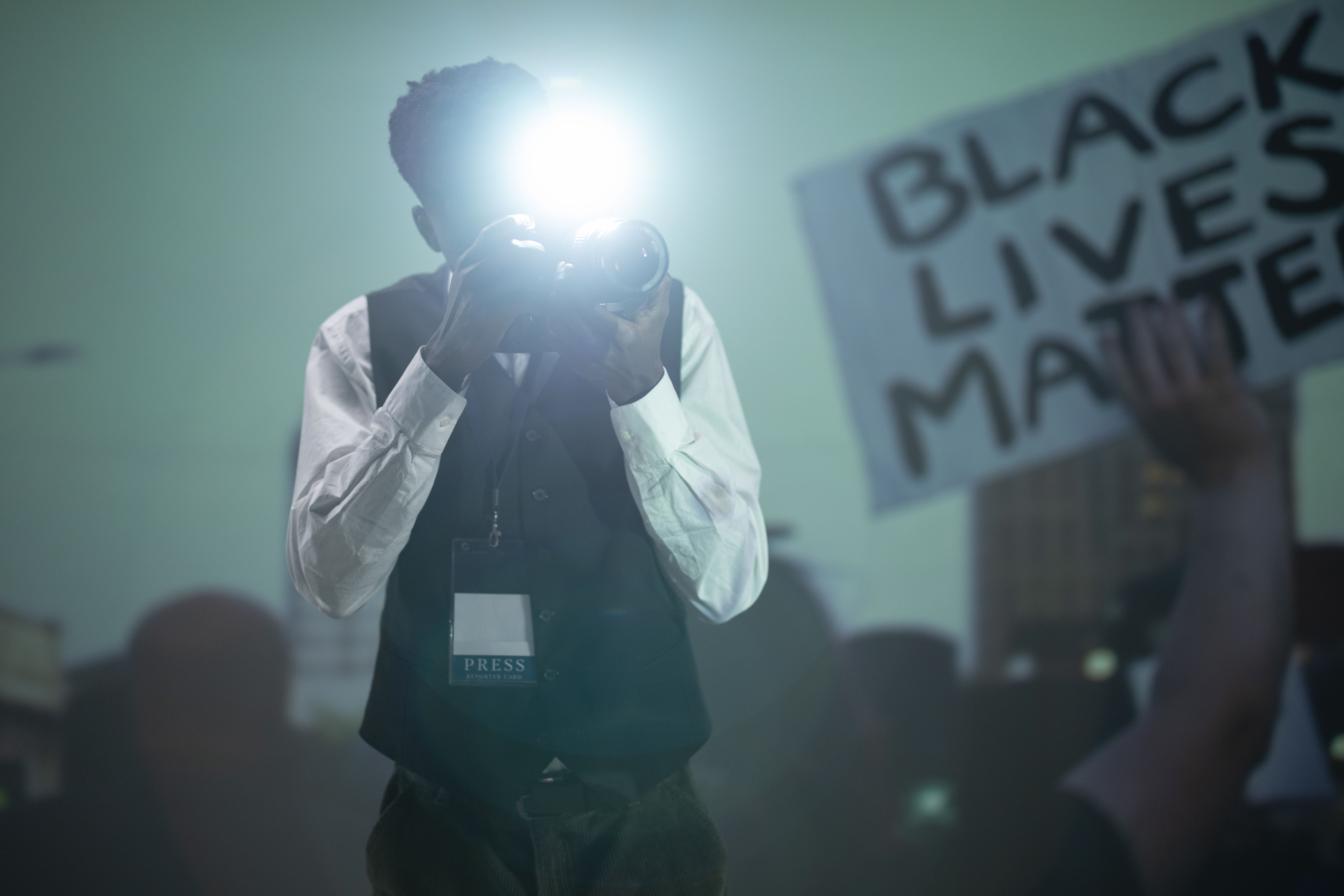 A photojournalist documenting a public protest, illustrating risks faced by reporters