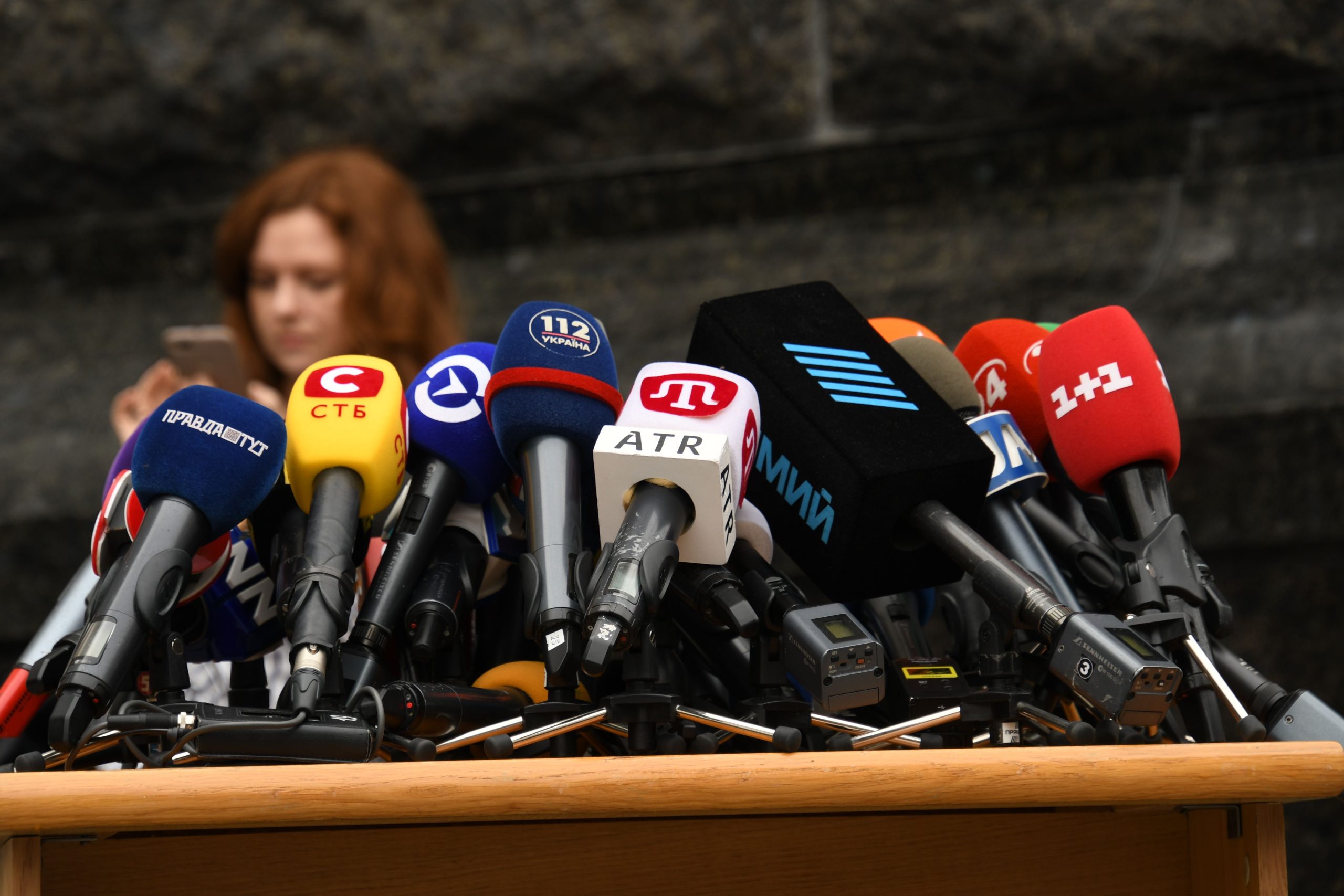 Rows of microphones at a press conference in Kyiv, representing journalists questioning public officials
